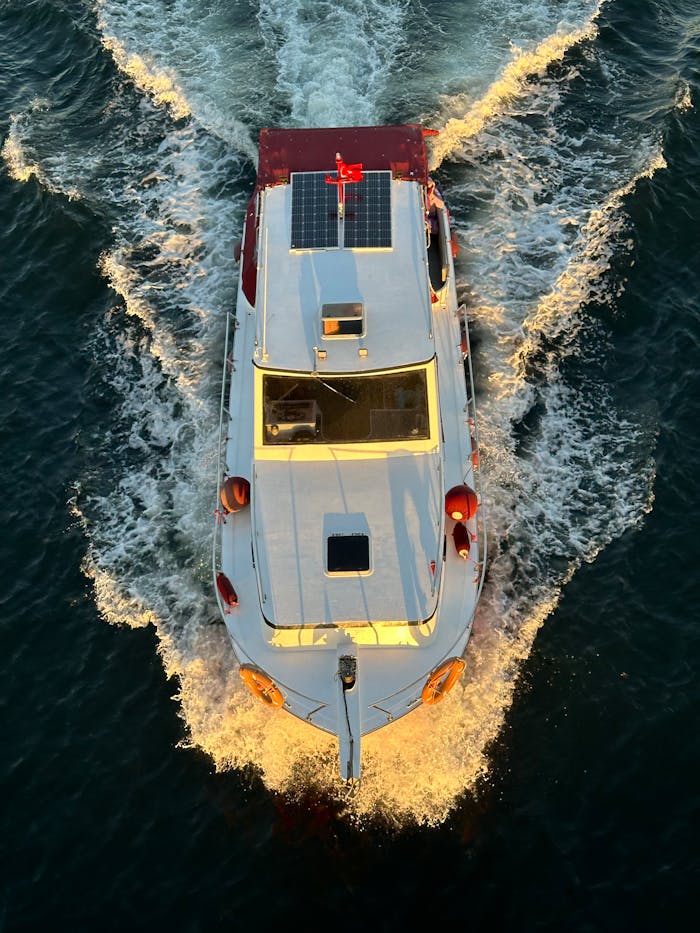 Aerial shot of a motorboat with solar panels cruising through waves at sea.