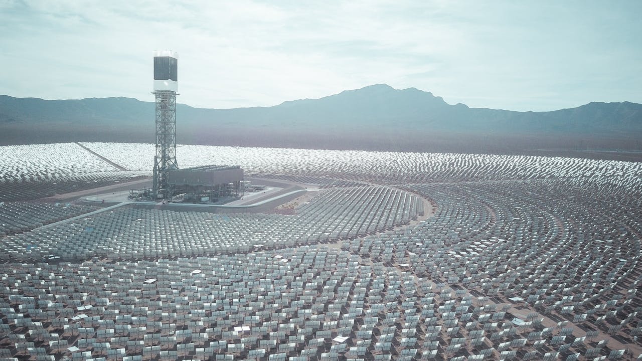 Wide aerial shot of a vast solar power station with mountain backdrop.