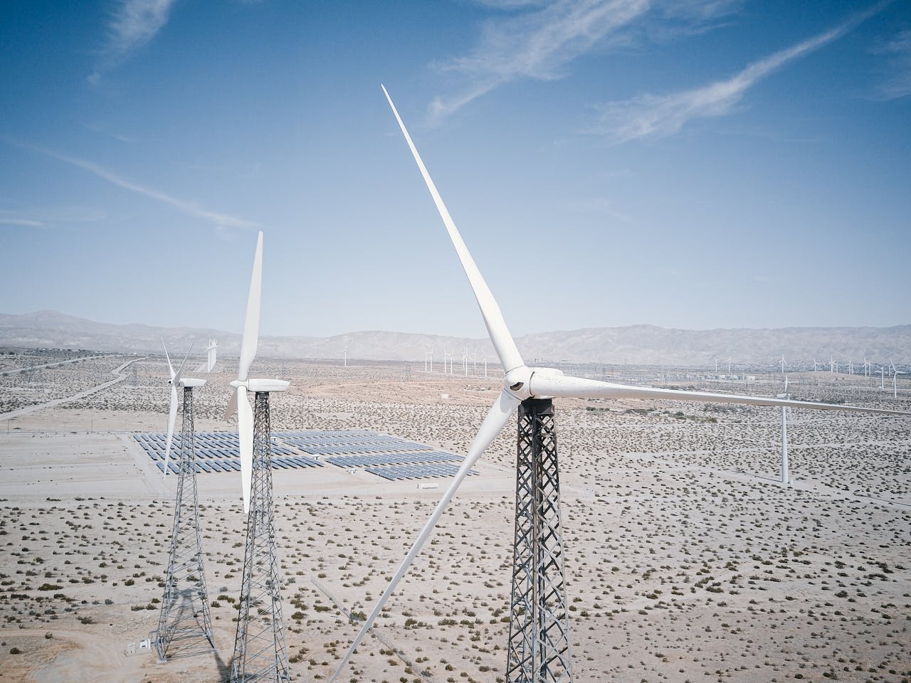 Wind turbines and solar panels generating renewable energy in a desert landscape.